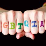 Unes mans porten dibuixades les sigles de la comunitat LGBTQIA+
